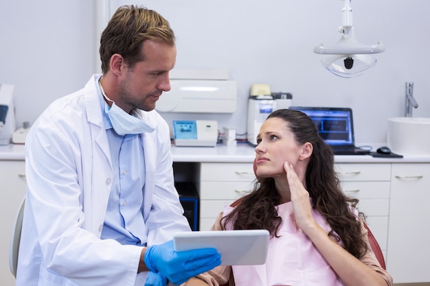 Dentista discutendo su tavoletta digitale con paziente di sesso femminile