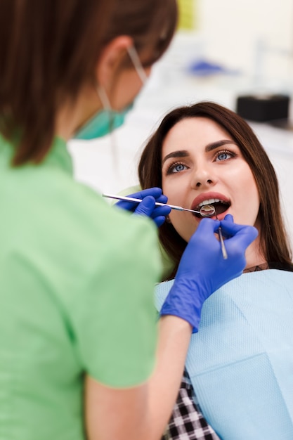 치과 의사는 구강 검사를합니다. 예쁜 환자 여자 치과 의사의 약속에 온