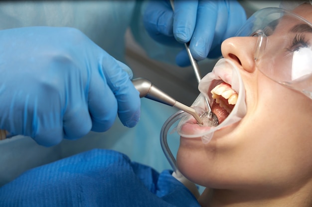 Dentista che fa un trattamento dentale su una paziente di sesso femminile. dentista che esamina i denti di un paziente nell'ufficio di odontoiatria moderna