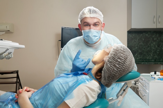 Дантист делает стоматологическое лечение пациентке. Стоматолог исследует зубы пациента в современном стоматологическом кабинете