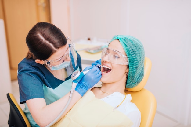 Dentist drilling teeth of female patient 