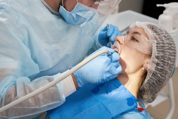 Photo dentist drilling tooth to male patient in dental chair