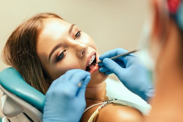 Photo dentist examine female patient with braces in denal office.