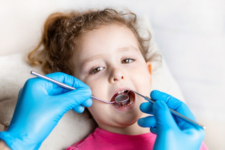 Dentist examines girl's teeth with tools