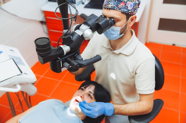 The dentist examines the patient\'s mouth with a dental\
microscope dental treatment the concept of healthy teeth microscope\
in dentistry