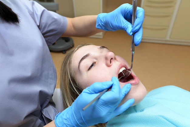 The dentist examines the patients teeth in the dental office Dental treatment