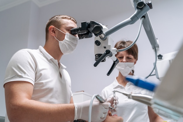 The dentist examines the patients teeth with a dental microscope.