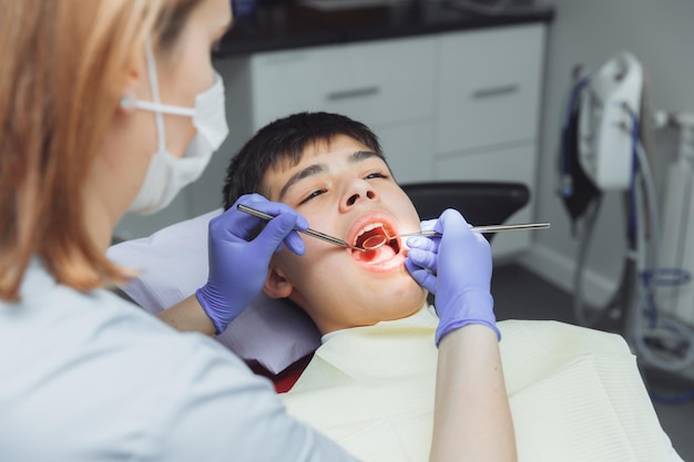 The dentist examines the teeth of a boy of 13 years old in the clinic pediatric dentistry