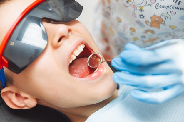 The dentist examines the teeth of a boy of 13 years old in the clinic pediatric dentistry