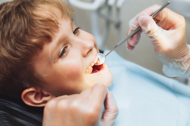 치과 의사는 클리닉 소아 치과에서 13세 소년의 치아를 검사합니다