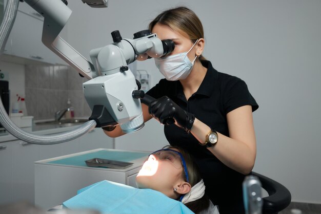 The dentist examines teeth of the child with a microscope. Professional dental equipment.