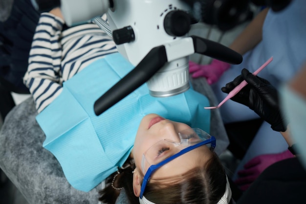 The dentist examines teeth of the child with a microscope Professional dental equipment