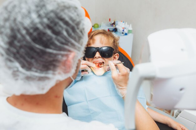 Il dentista esamina i denti di un ragazzino in una moderna odontoiatria clinicapediatrica