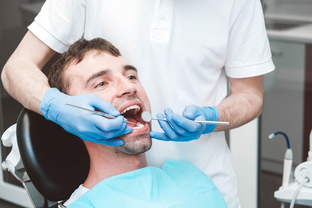 Dentist examines the teeth of a male patient on a dentist's chair. Copy, empty space for text