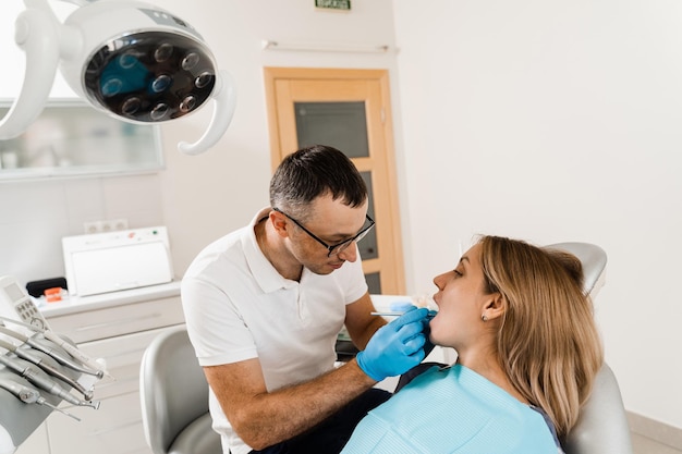 Dentist examines teeth of woman for treatment of toothache pain\
in teeth consultation with dentist in dentistry