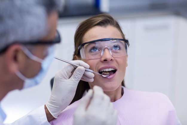 Dentist examining a female patient with tools