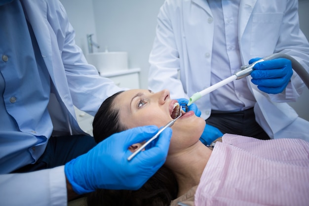 Dentist examining a female patient with tools