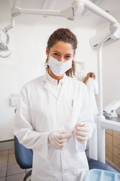 Dentista esaminando i suoi strumenti su un vassoio che guarda l'obbiettivo