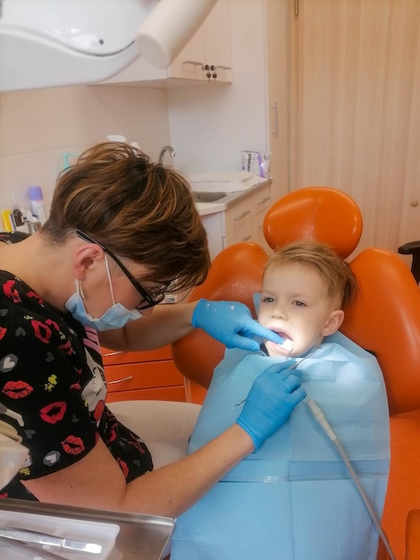 Photo dentist examining little boy's teeth in clinic