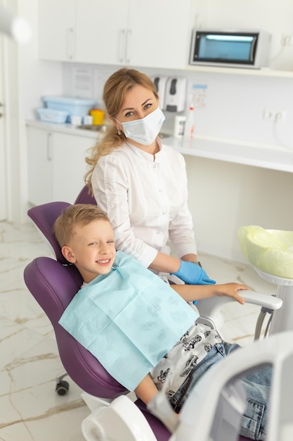 現代のクリニックで小さな男の子の歯を調べる歯科医