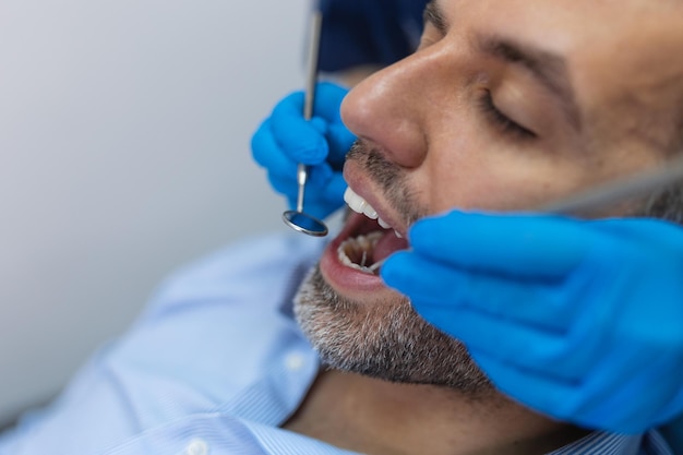 Photo dentist examining a patient's teeth in the dentist office man patient having dental treatment at dentist's office