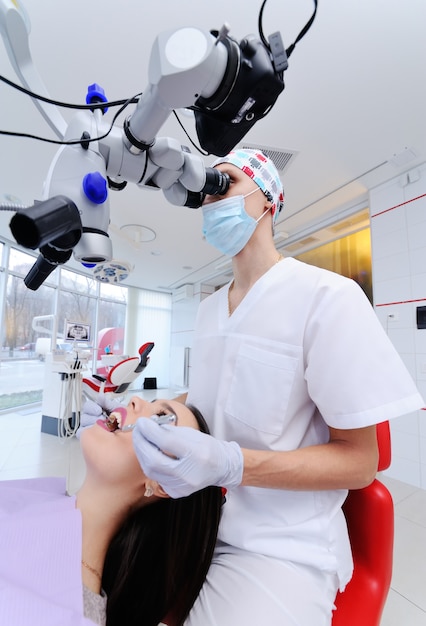 Dentist examining patient's teeth through dental microscope