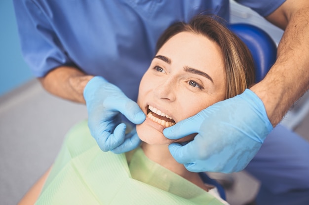 Dentista che esamina i denti di un paziente facendo uso dell'attrezzatura dentale nell'ufficio di odontoiatria