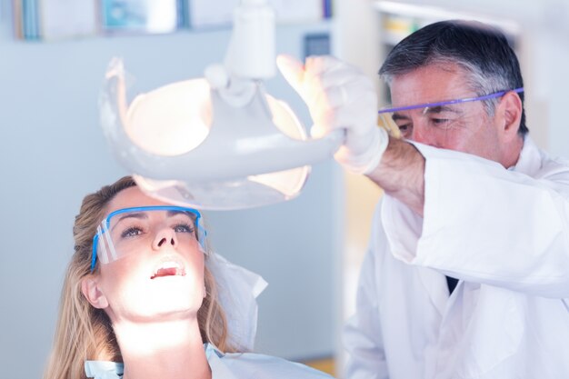 Dentist examining a patients teeth in chair under bright light