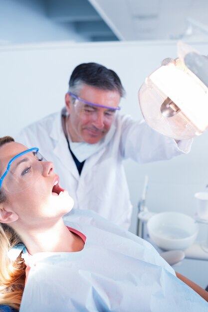 Dentist examining a patients teeth in chair under bright light