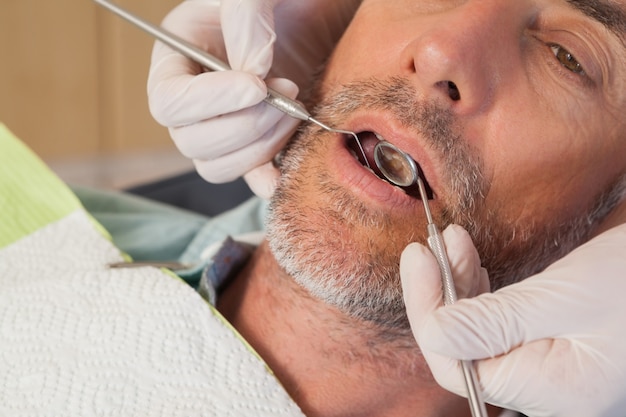 Foto dentista che esamina i denti dei pazienti nella sedia dei dentisti