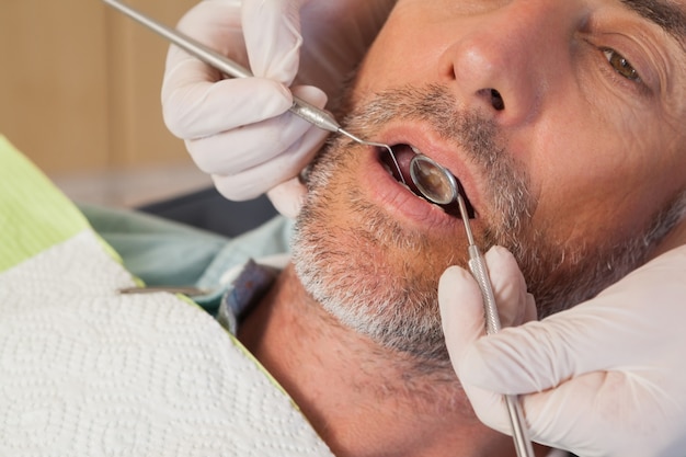 Photo dentist examining a patients teeth in the dentists chair