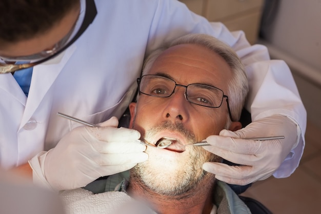 Dentist examining a patients teeth in the dentists chair