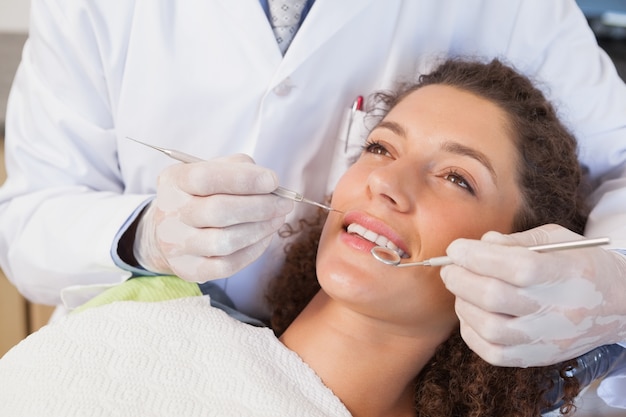 Dentist examining a patients teeth in the dentists chair