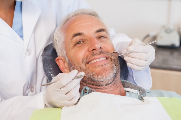 Dentist examining a patients teeth in the dentists chair