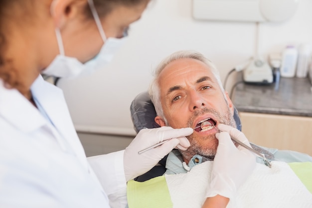 Dentist examining a patients teeth in the dentists chair