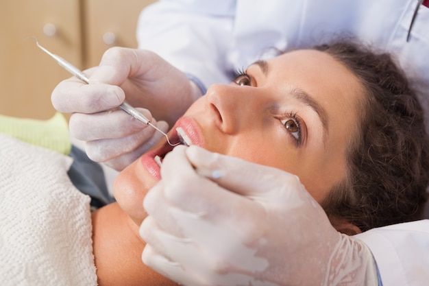 Dentist examining a patients teeth in the dentists chair