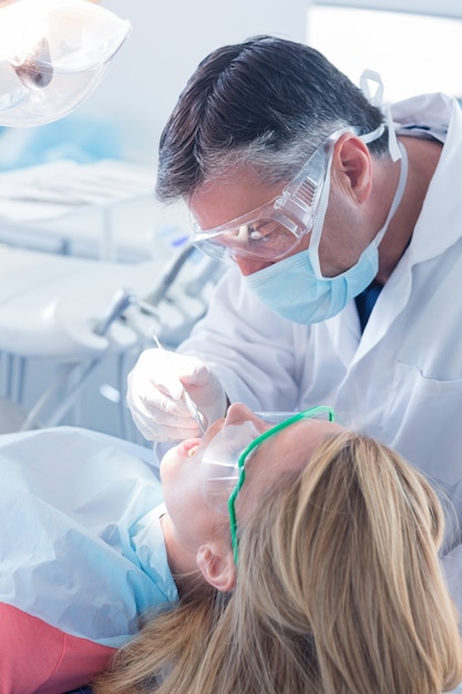 Dentist examining a patients teeth in the dentists chair