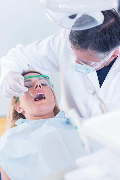 Dentist examining a patients teeth in the dentists chair