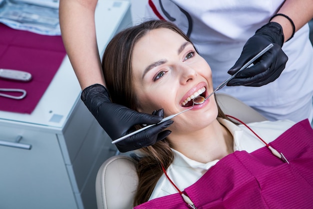 Фото Стоматолог осматривает зубы молодой пациентки в стоматологической клинике концепция стоматологии
