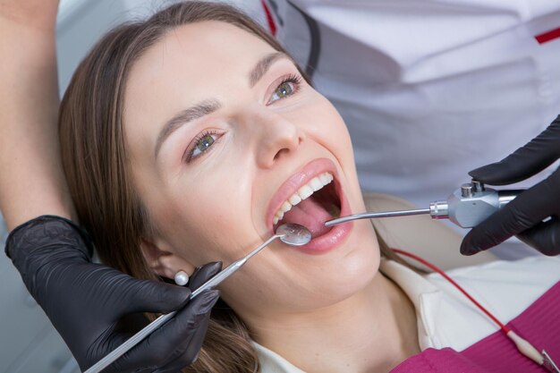 Photo dentist examining teeth of a young woman patient in a dental clinic dentistry concept