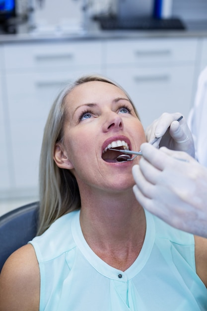 Стоматолог осматривает женщину с инструментами