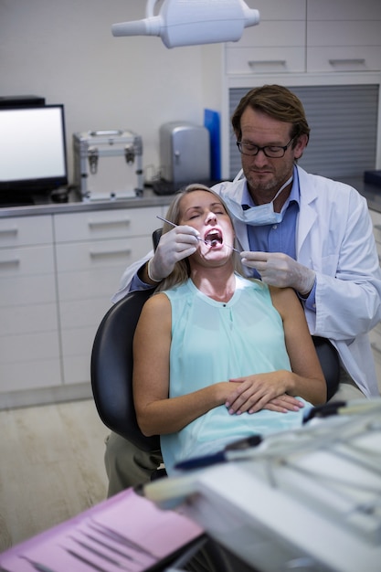Стоматолог осматривает женщину с инструментами