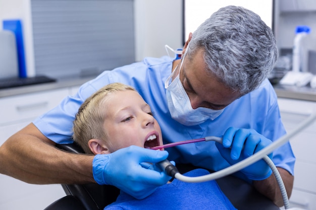 Foto dentista che esamina un giovane paziente con gli strumenti