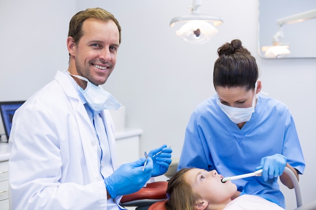 Photo dentist examining a young patient with tools