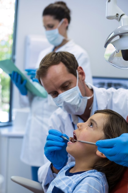 Dentista che esamina un giovane paziente con gli strumenti