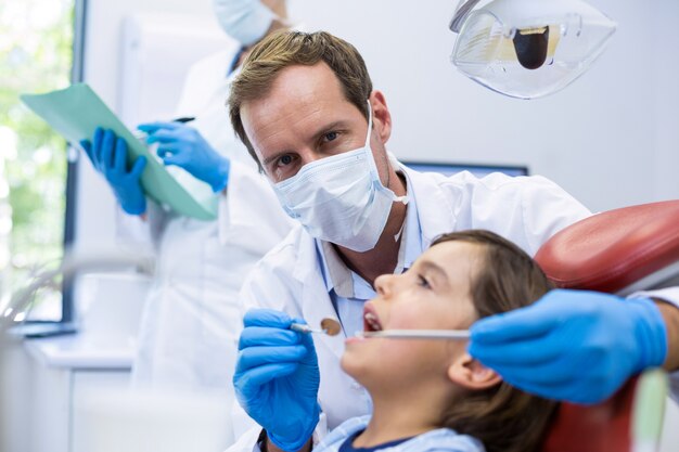 Dentist examining a young patient with tools