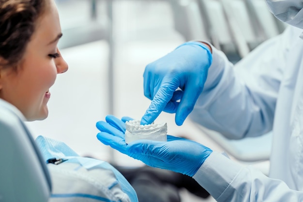 Dentist explaining the details of dental mold to his patient Close up view