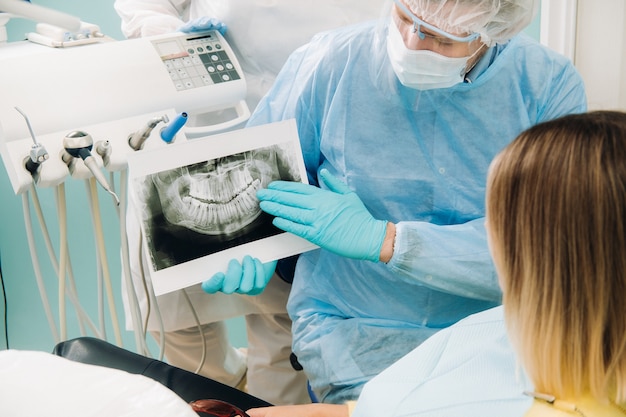 Dentist explaining the details of the X-ray to his patient in the office.