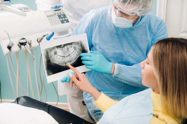 Стоматолог объясняет детали рентгеновского снимка своему пациенту в офисе.