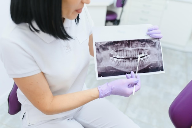 Dentist explaining the details of a xray teeth picture to his patient in clinic Oral care orthodontics